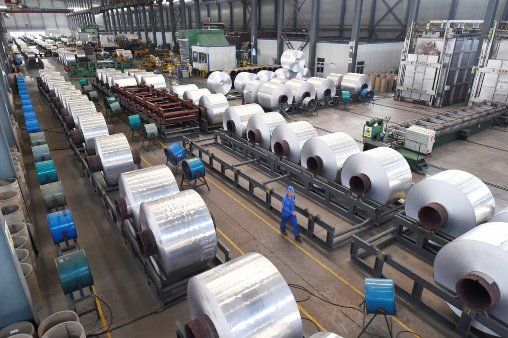 Home workers are seen next to aluminium rolls at a plant in binzhou